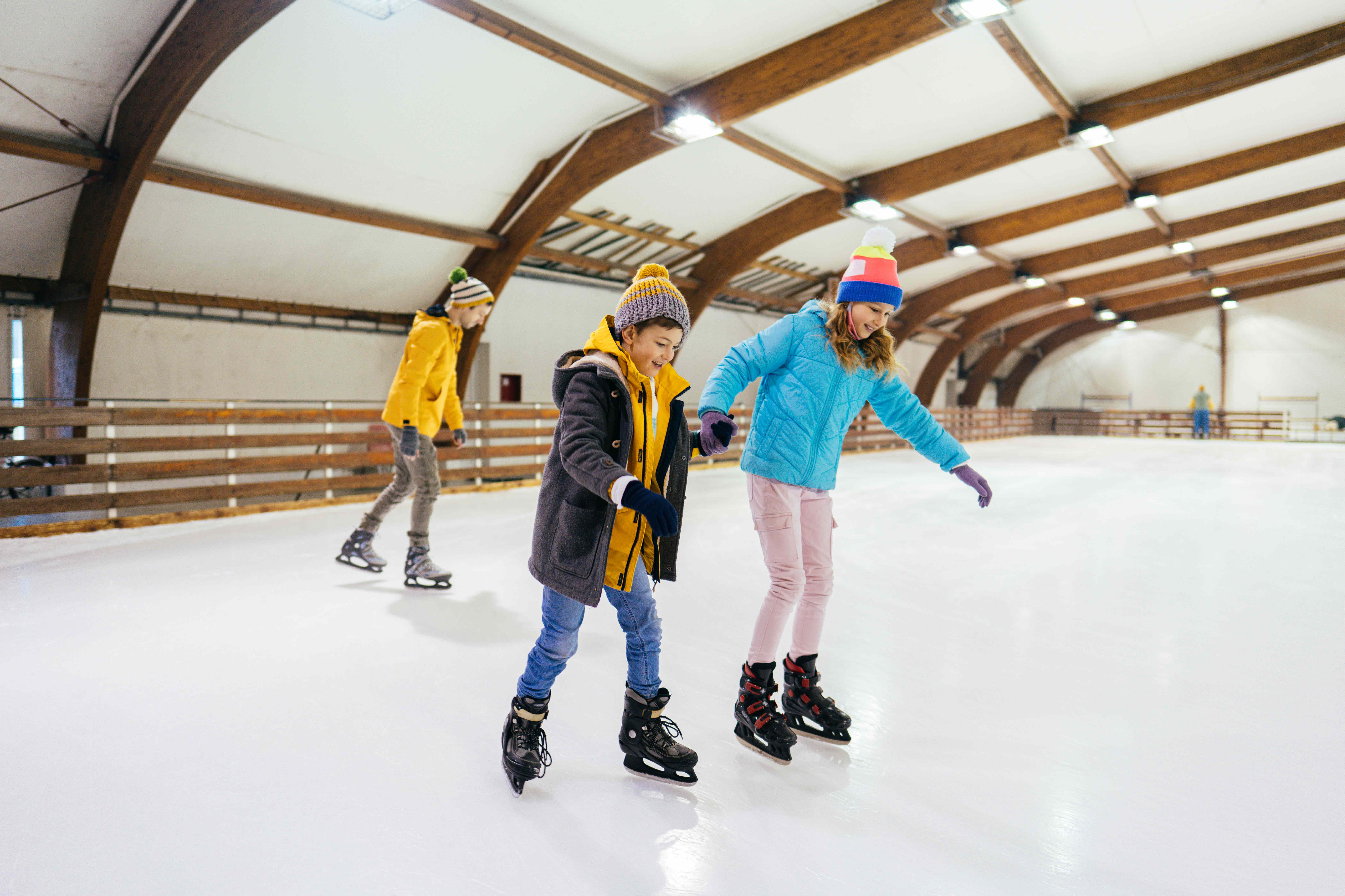 Broer en zus aan het schaatsen op het ijs in een schaatsbaan